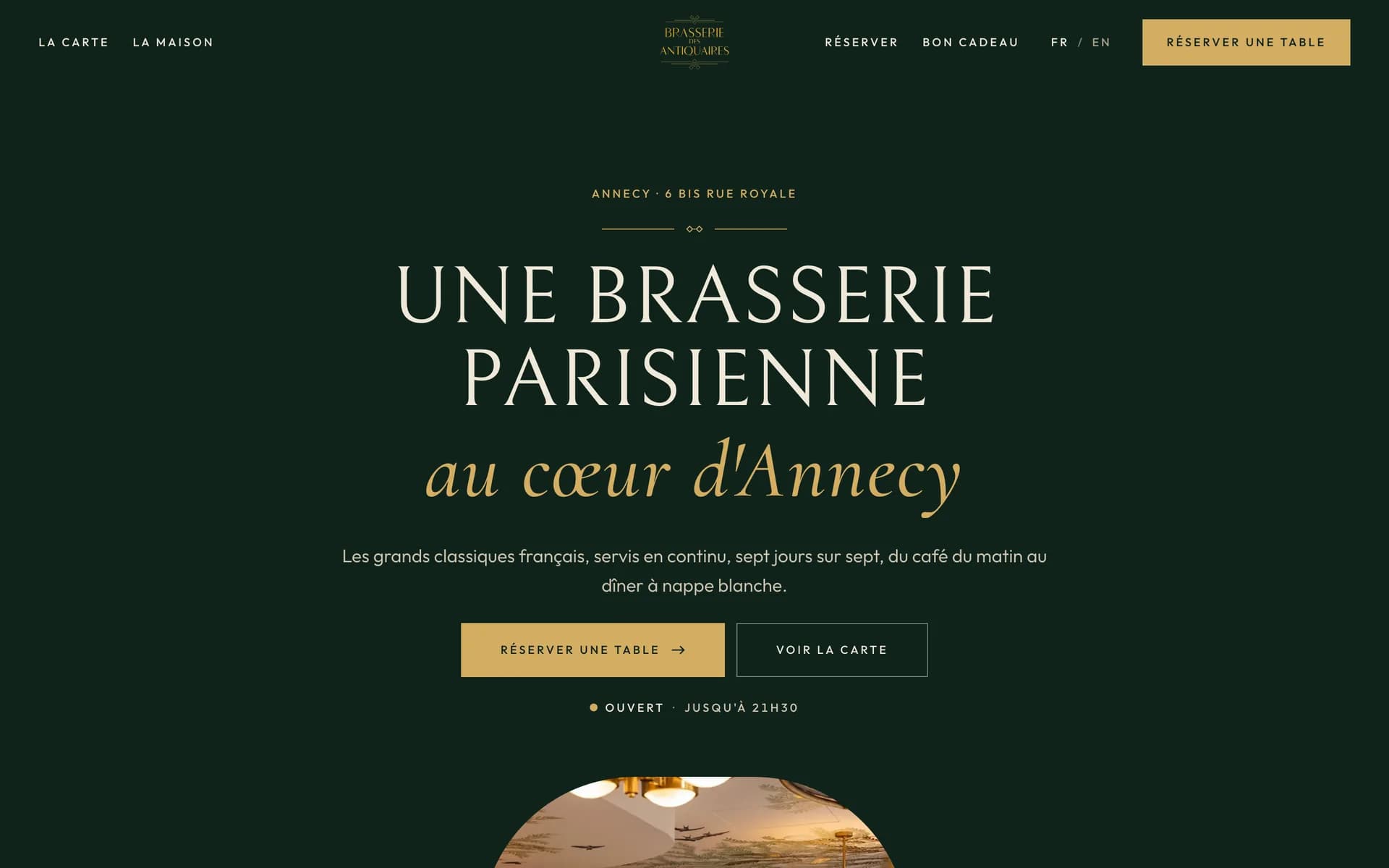 Page d’accueil de la Brasserie des Antiquaires : « Une brasserie parisienne au cœur d’Annecy » en capitales claires et en italique doré sur fond vert sombre, avec les boutons « Réserver une table » et « Voir la carte ».
