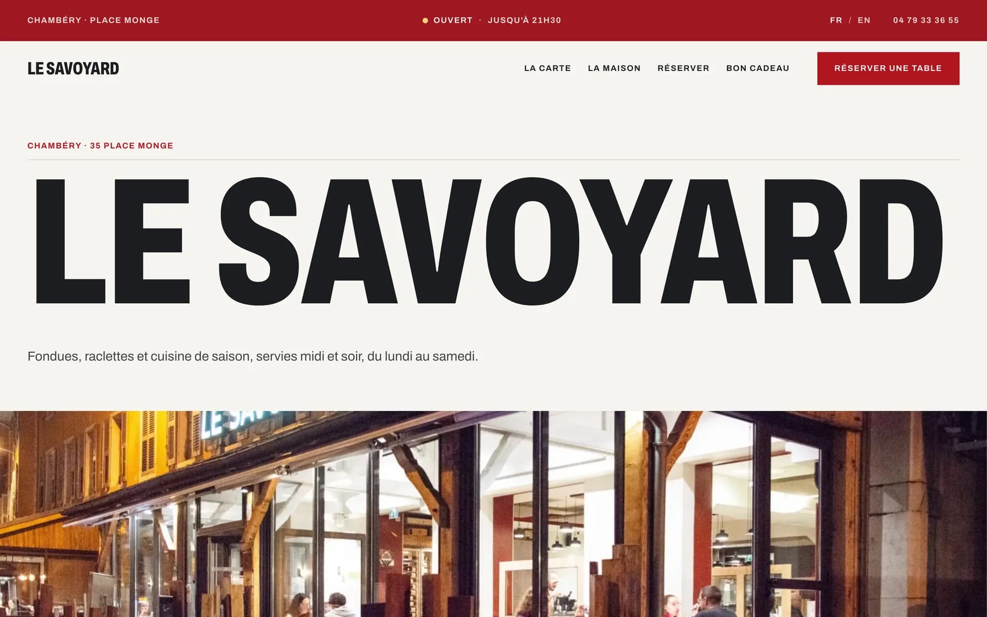 Page d’accueil du Savoyard : « Le Savoyard » en très grandes capitales noires sur fond crème, sous un bandeau rouge, au-dessus d’une photographie de la devanture éclairée.